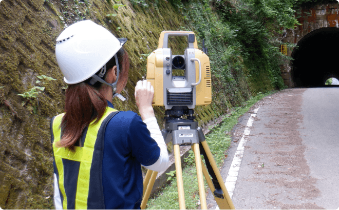 地上レーザスキャナで道路トンネル周辺を三次元計測する測量作業員